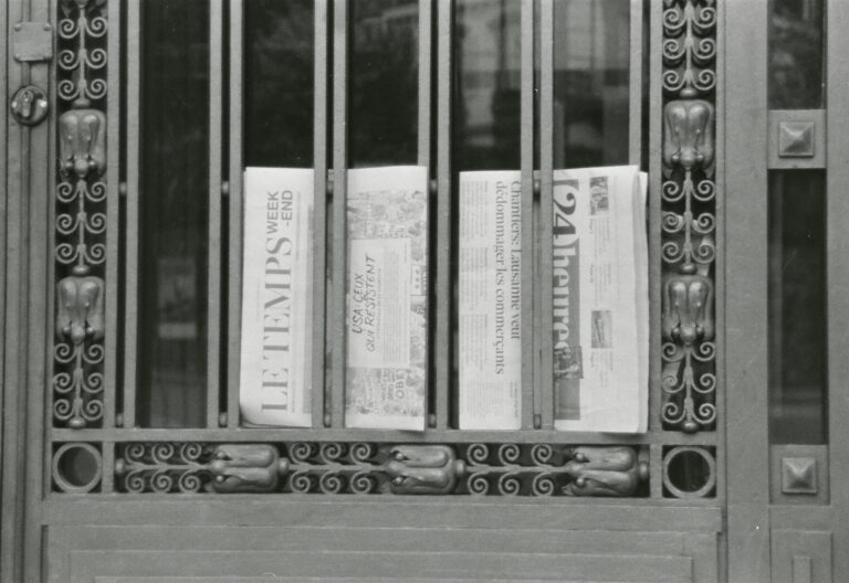 Newspapers behind ornate metal gate