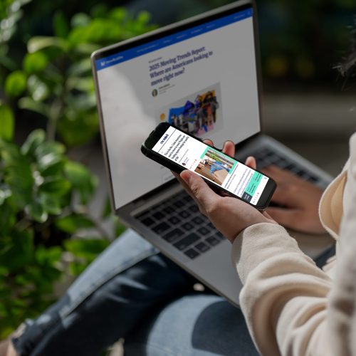 Close-up image of an Asian woman using her smartphone and laptop while sitting in her home garden. People and technology concepts