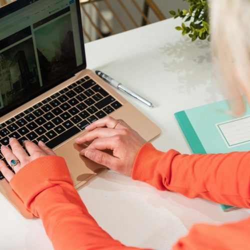 person in orange long sleeve shirt using macbook pro